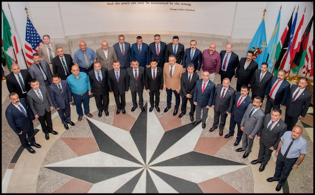 seminar participants standing for a group photo around flags